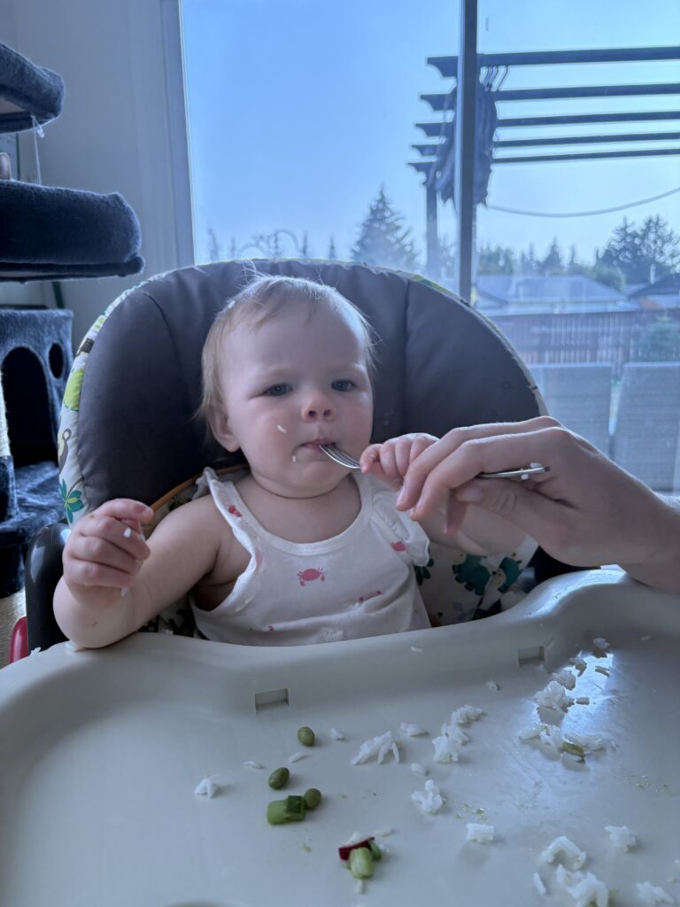 Roslyn enjoying HelloFresh Bang Bang Tofu Tacos baby review with her fork, showing off her big kid skills.